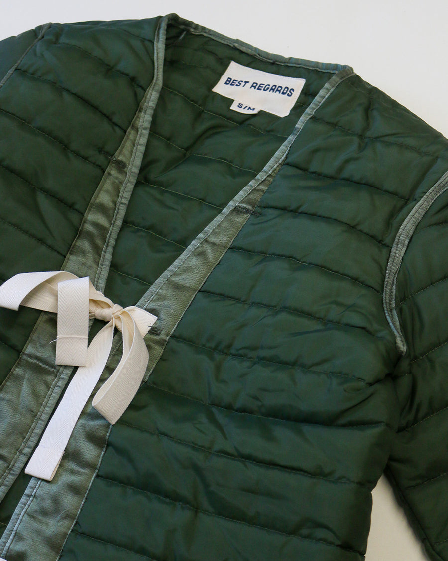 up close of green quilted jacket with white double bow closure