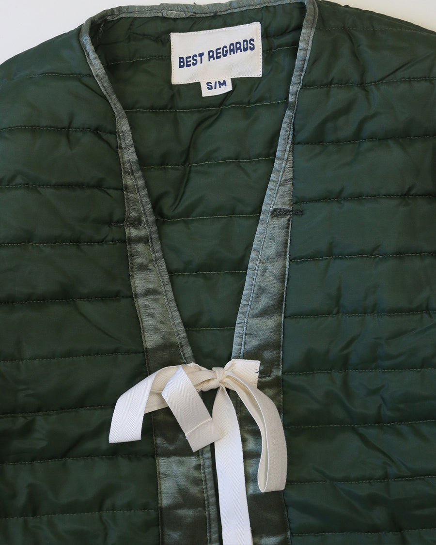 up close of green quilted jacket with white double bow closure