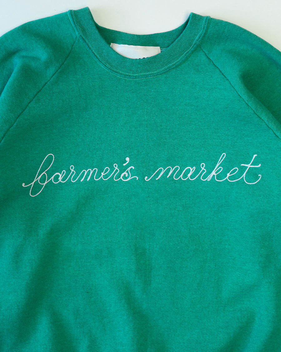 green sweatshirt with white chainstitch farmer's market across the front