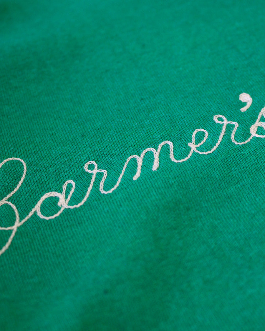 up close of green sweatshirt with white chainstitch farmer's market across the front