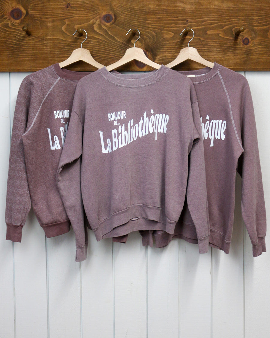 hanging rosewood sweatshirts with white Bonjour De La Bibliothèque across the front