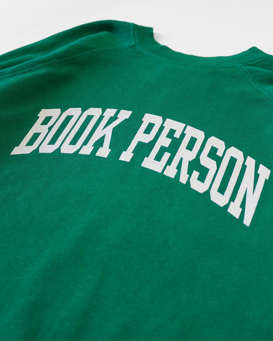 up close of kelly green sweatshirt with white 'BOOK PERSON' across the front