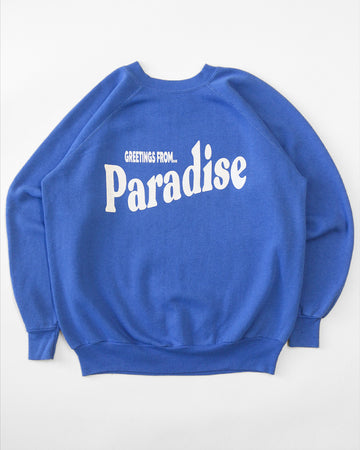 blue sweatshirt with white 'GREETING FROM...PARADISE' across the front