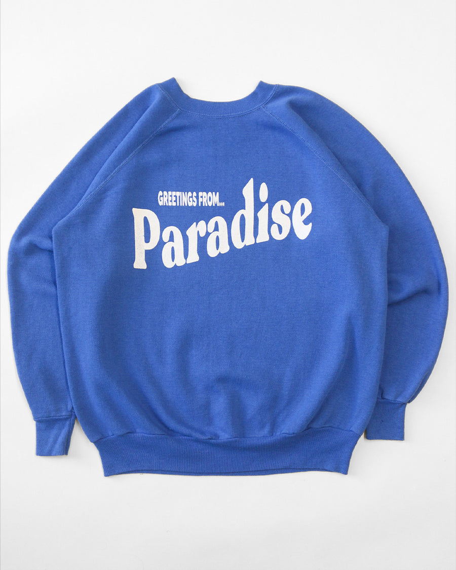 blue sweatshirt with white 'GREETING FROM...PARADISE' across the front