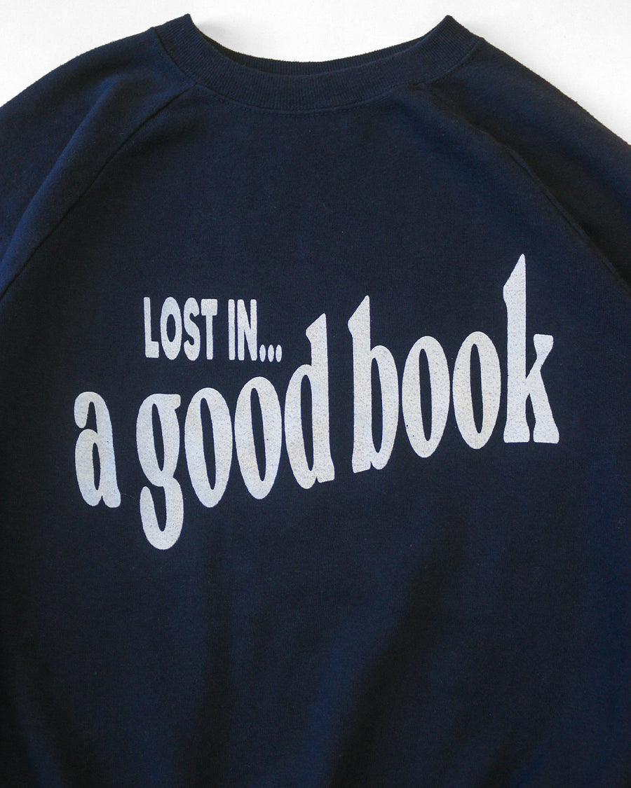 front view of navy sweatshirt with white 'LOST IN... GOOD BOOK' across the front