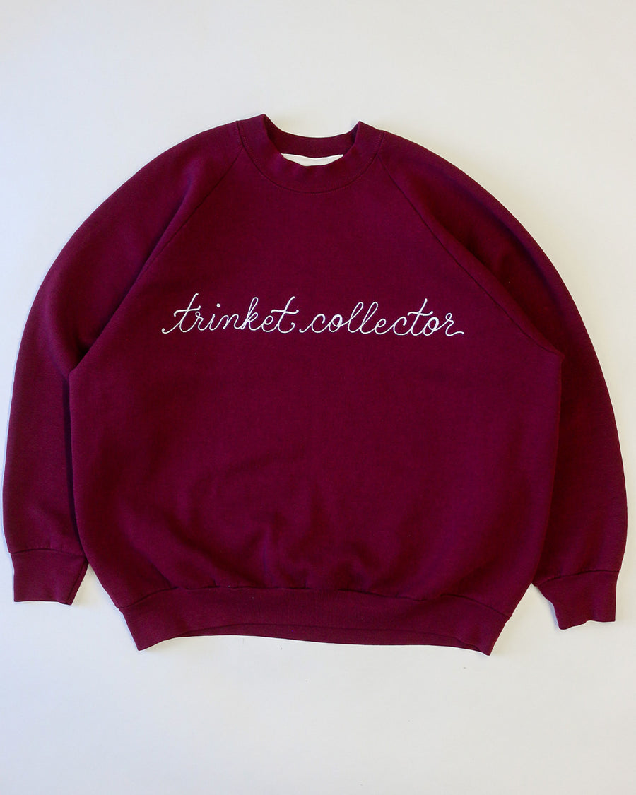 maroon sweatshirt with white chainstitch trinket collector across the front