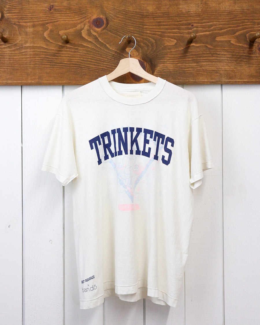 vintage white tee with navy TRINKETS across the front on a hanger