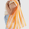 model carrying tangerine and white wide stripe big baggu