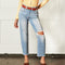 front view of model wearing light denim jeans with raw hem and distressing throughout