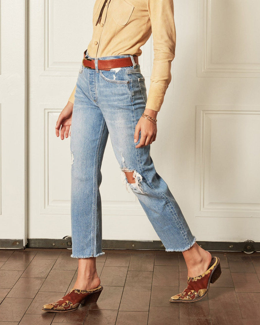 model wearing light denim jeans with raw hem and distressing throughout