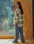 back view of model wearing brown and green plaid jacket with zipper front and patch pockets