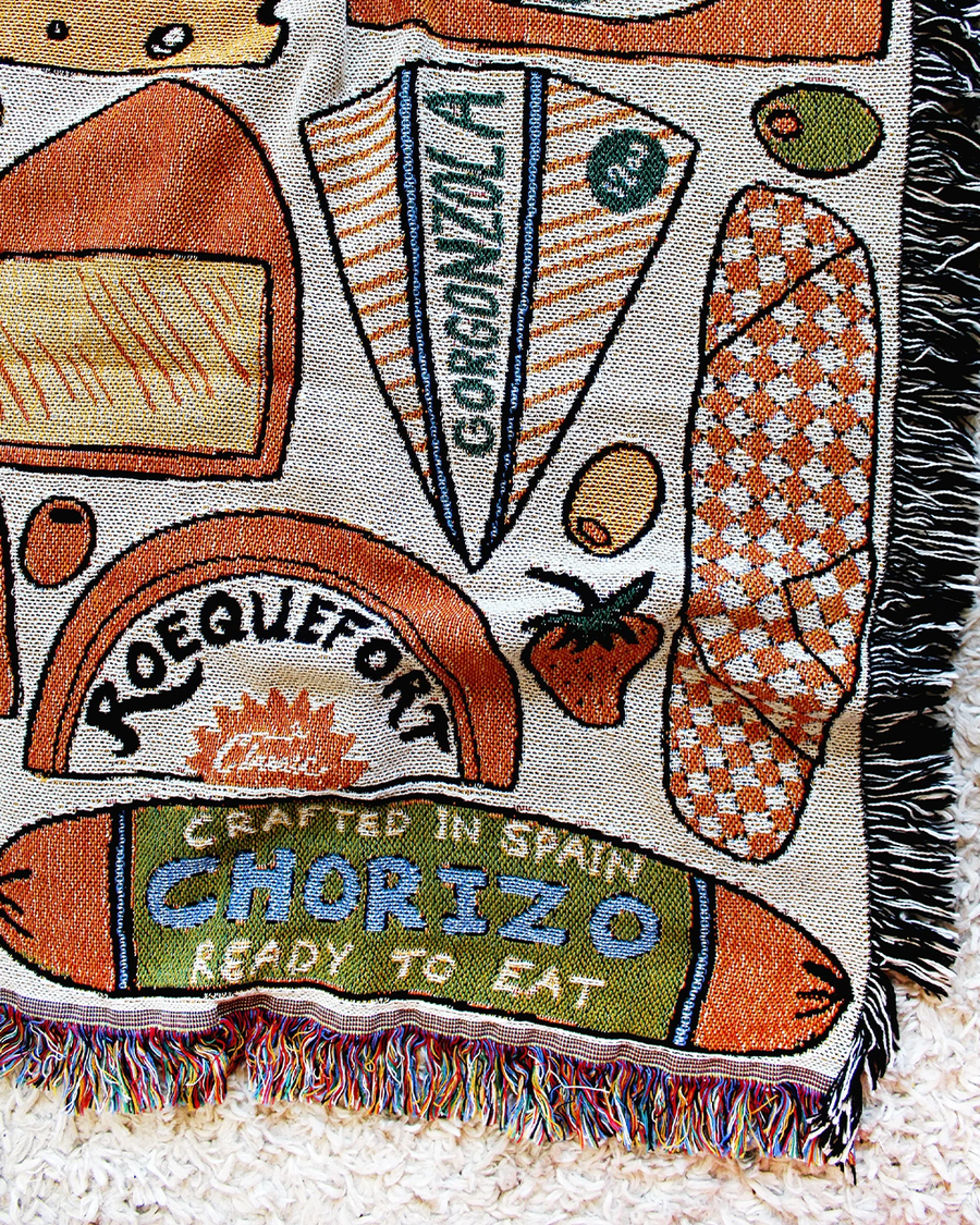 up close of white tapestry blankets with all over meat and cheese print and fringe edges