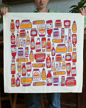 model holding tea towel with different condiment bottles