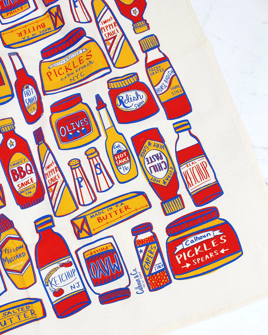 up close of tea towel with different condiment bottles
