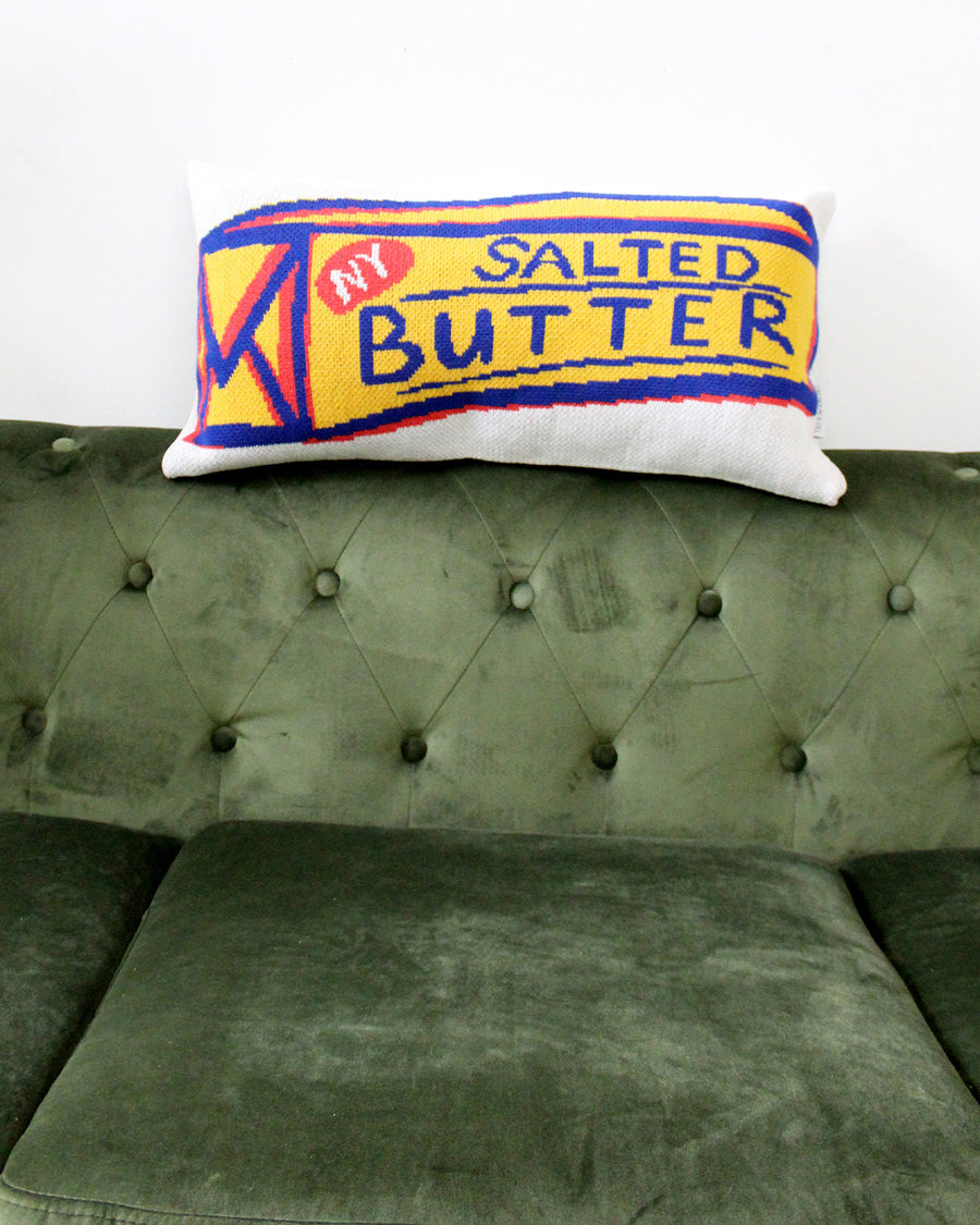 salted butter rectangular throw pillow on the back of a green couch
