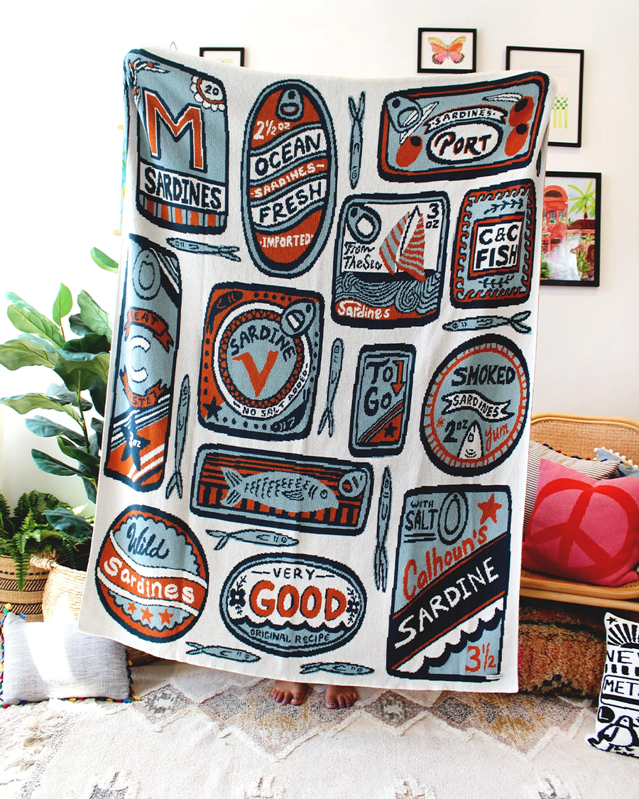 model holding white tea towel with orange and blue sardine can print