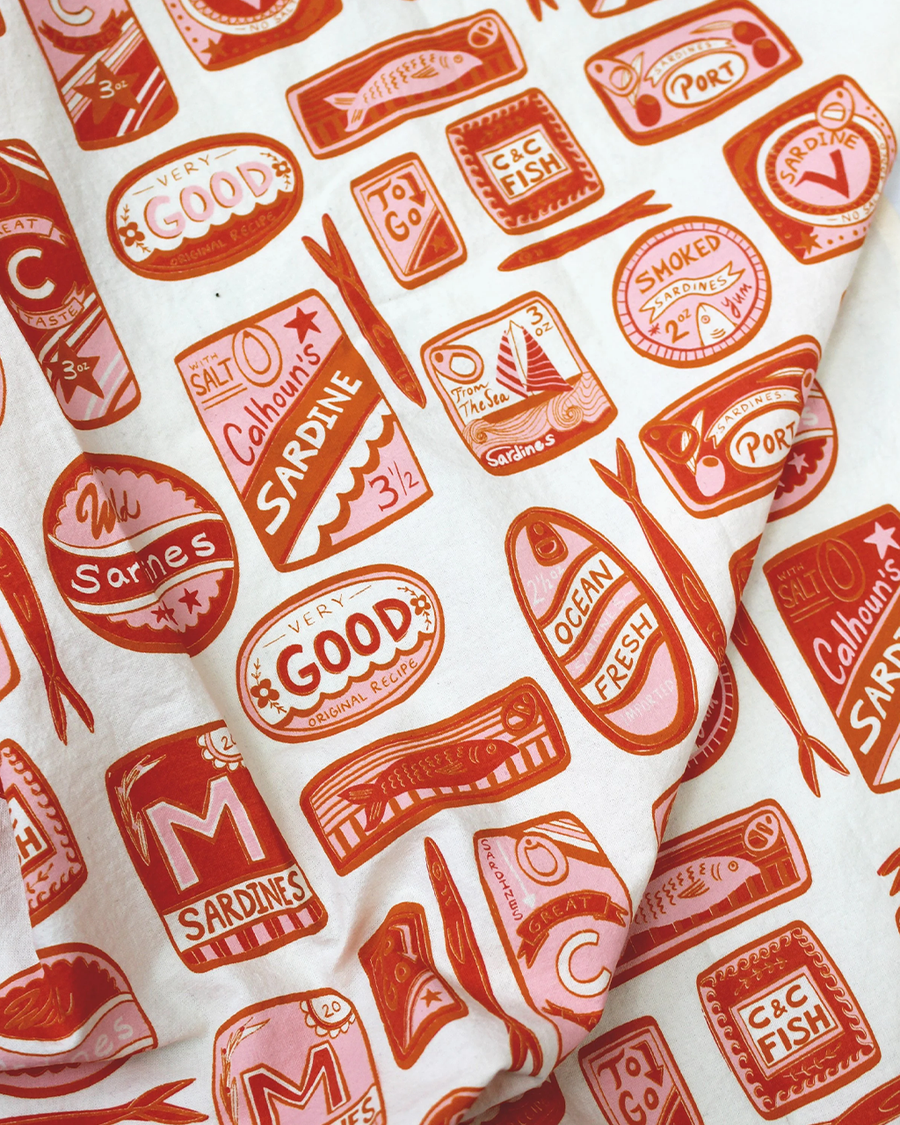 up close of cream tea towel with pink and red sardine can print