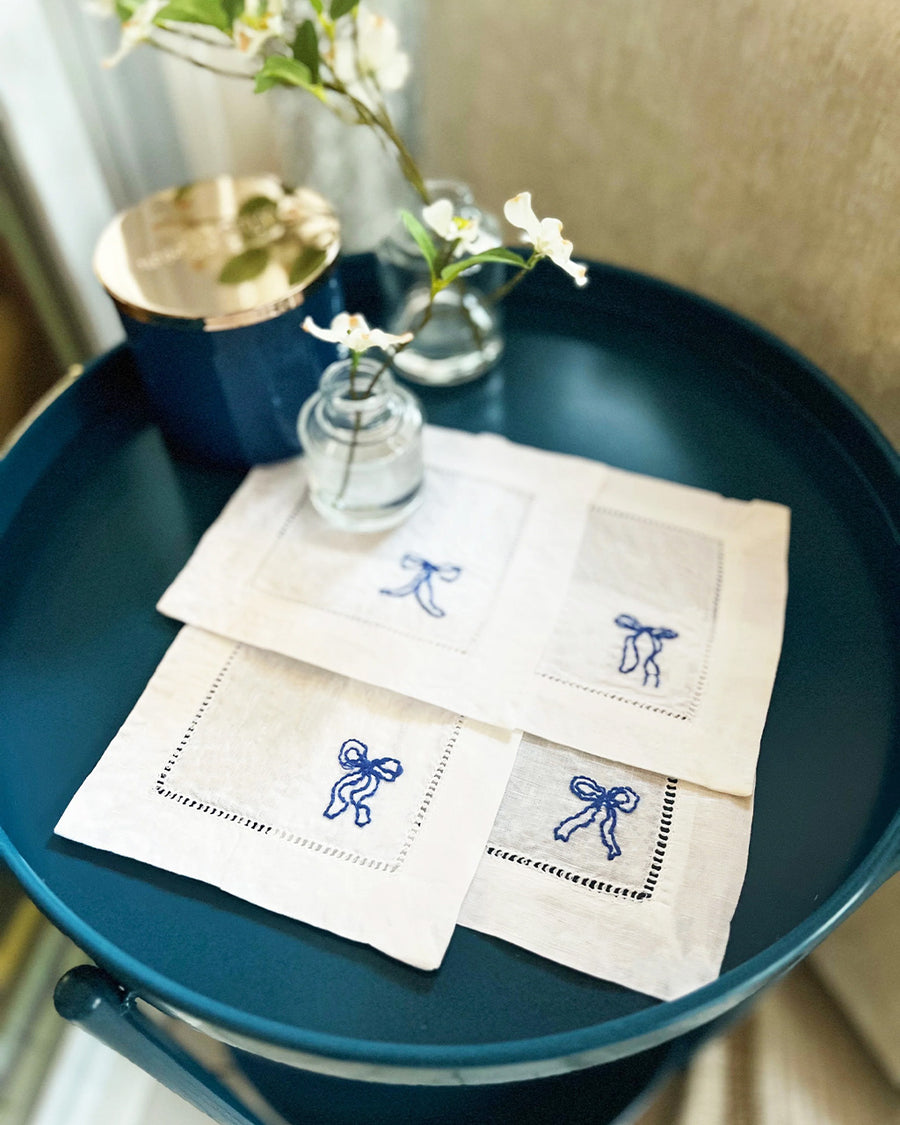 white napkins with dark blue embroidered bows on a table