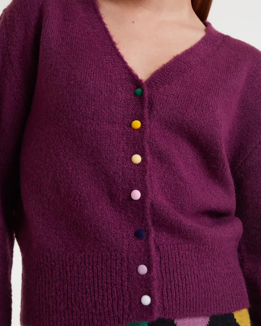 up close of model wearing fuzzy burgundy cardigan with colorful button front