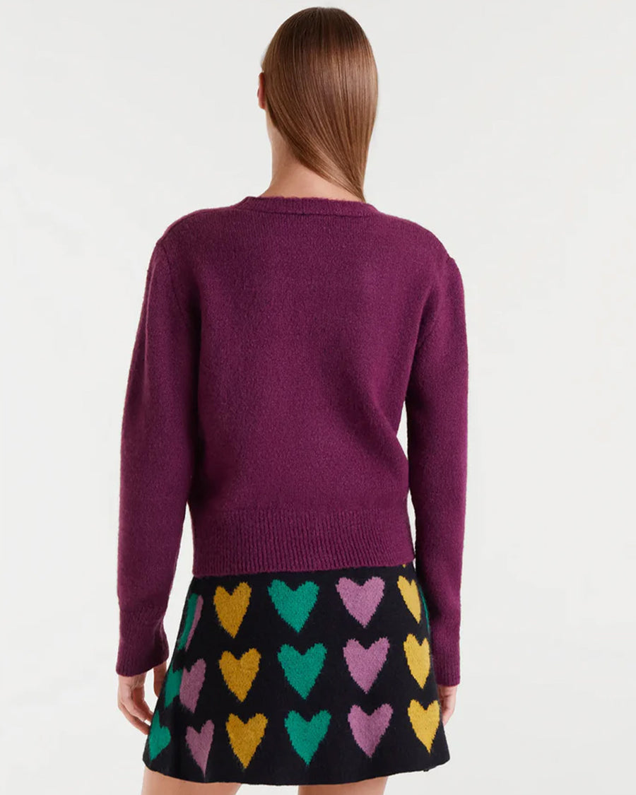 back view of model wearing fuzzy burgundy cardigan with colorful button front