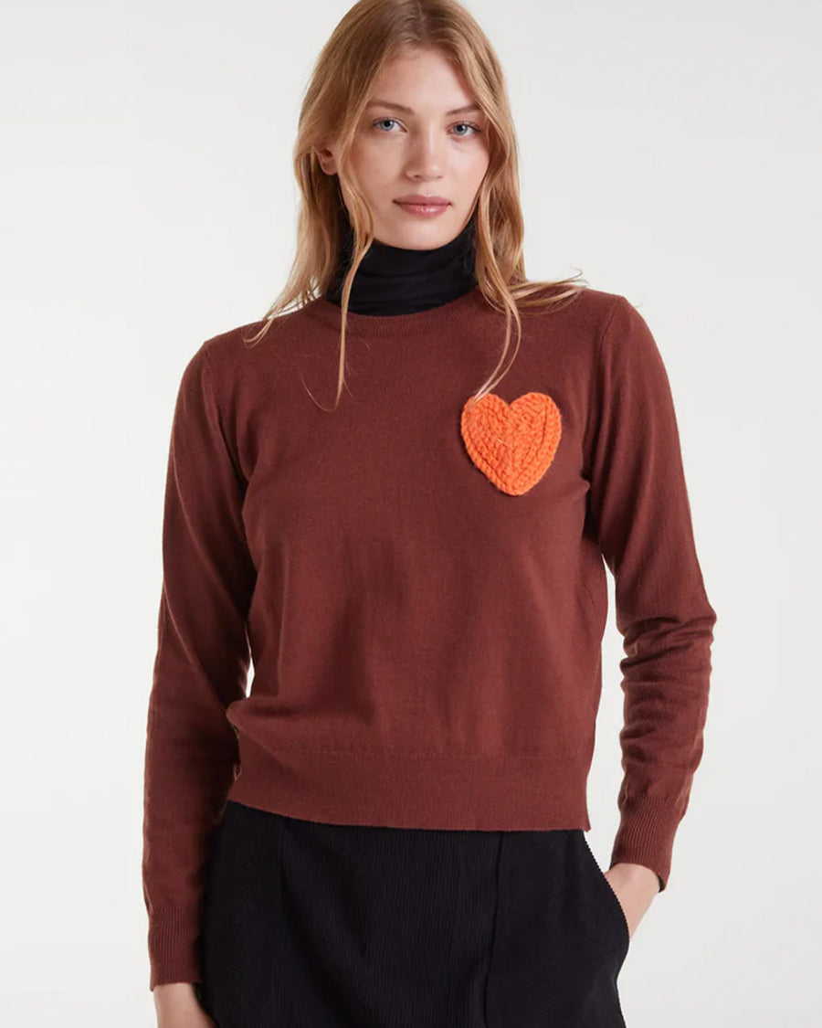model wearing brown sweater with textured orange heart on the left bust
