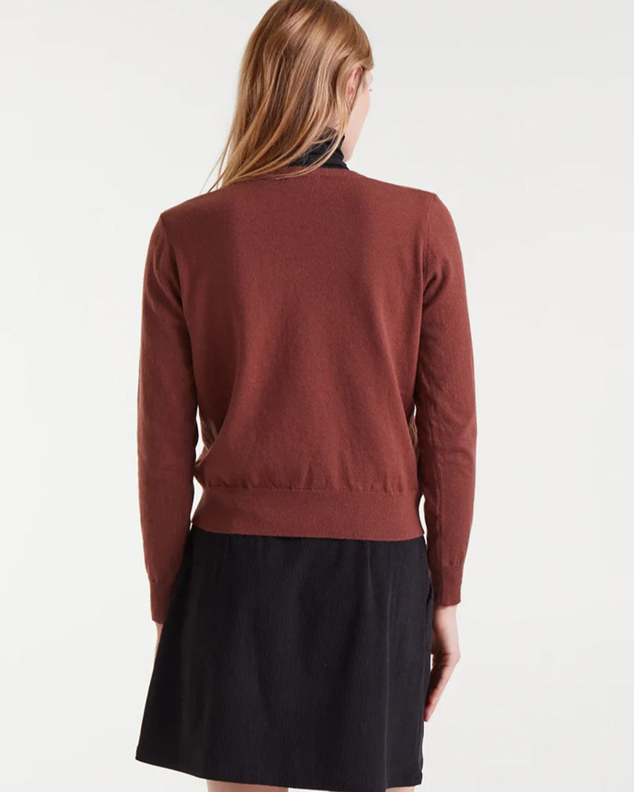 back view of model wearing brown sweater with textured orange heart on the left bust