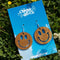 wooden smiley face dangle earrings laying on grass
