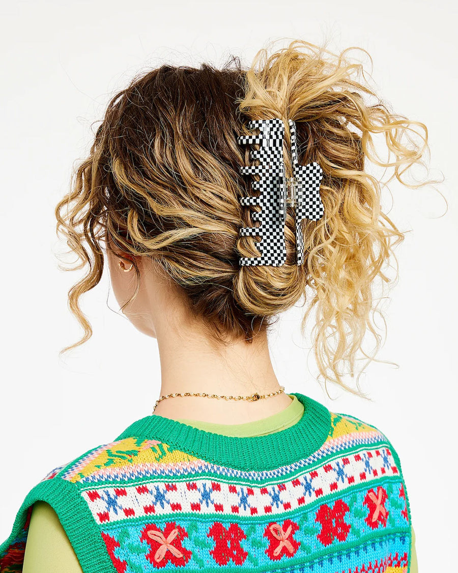 model wearing large black and white checkered hair claw with double row of teeth