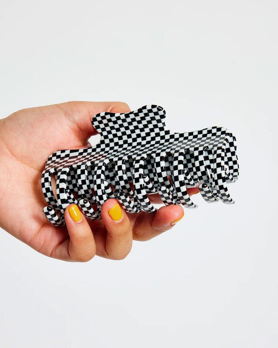 model holding large black and white checkered hair claw with double row of teeth
