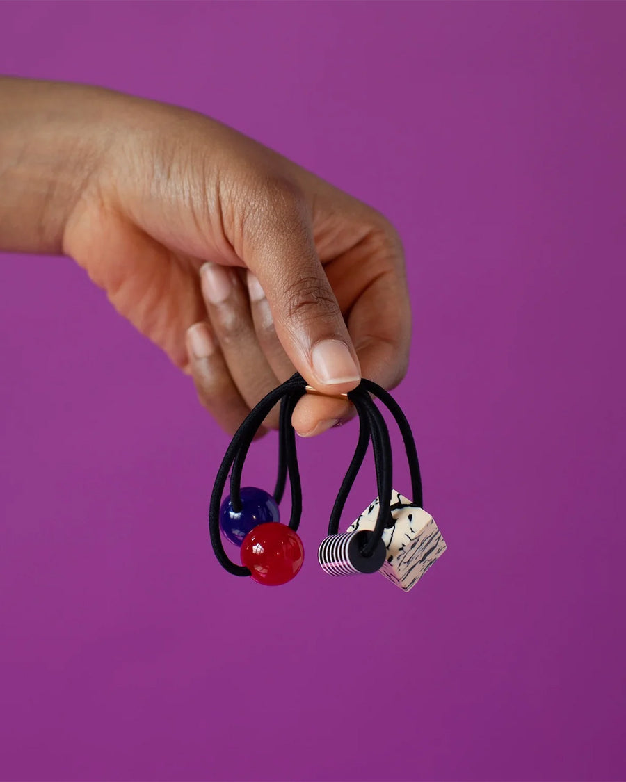 model holding bobble ties with black and white, red, blue and square cream and black beads