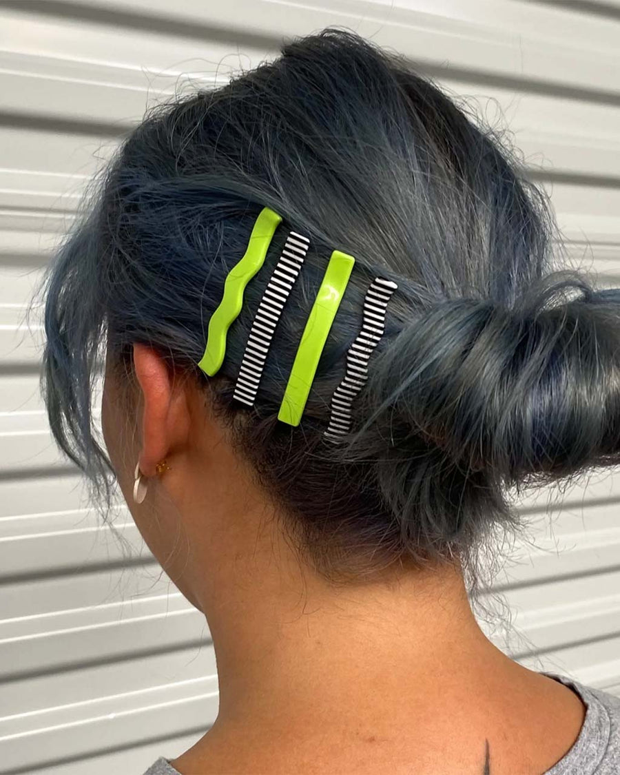 model wearing set of four hair clips: lime green wavy, lime green straight, black and white stripe wavy, and black and white stripe straight