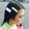 model wearing set of two yellow alligator hair clips with clear blue overlay