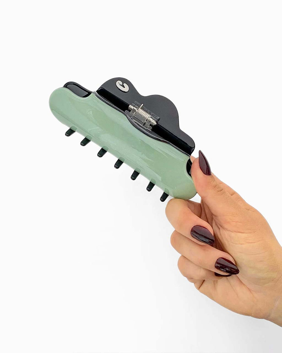 model holding matte light green large hair claw with black inside