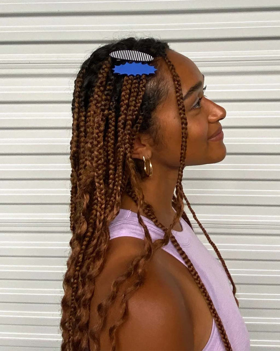 model wearing set of two hair clips: bright blue pointed action blurb and oval black and white stripes