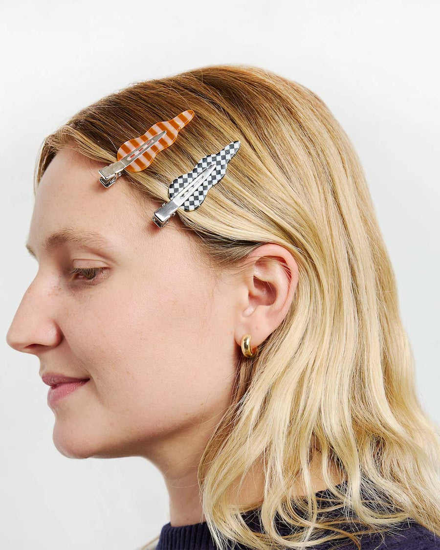 model wearing orange and pink stripe and black and white checkered setting clips