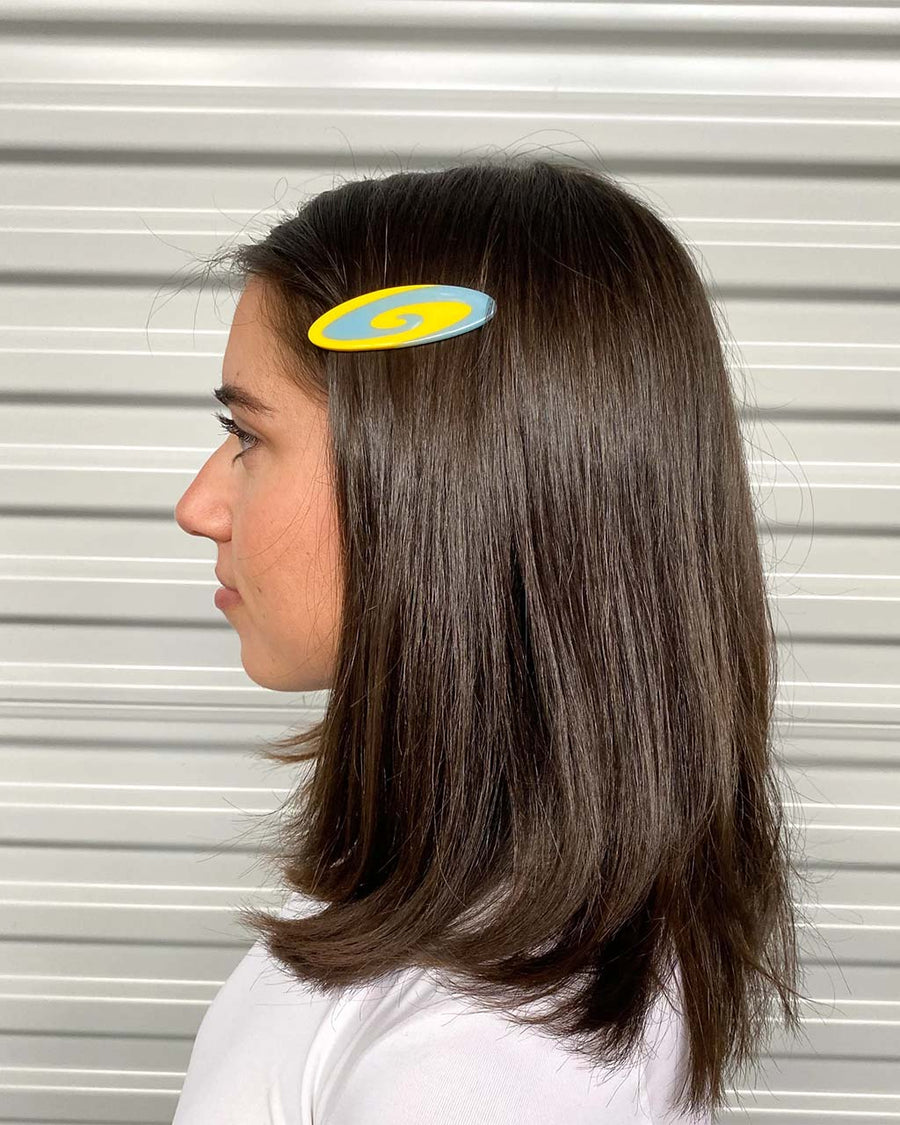 model wearing blue and yellow swirl oval hair clip