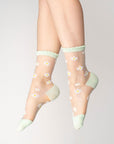 model wearing sheer crew socks with all over daisy print and white trim