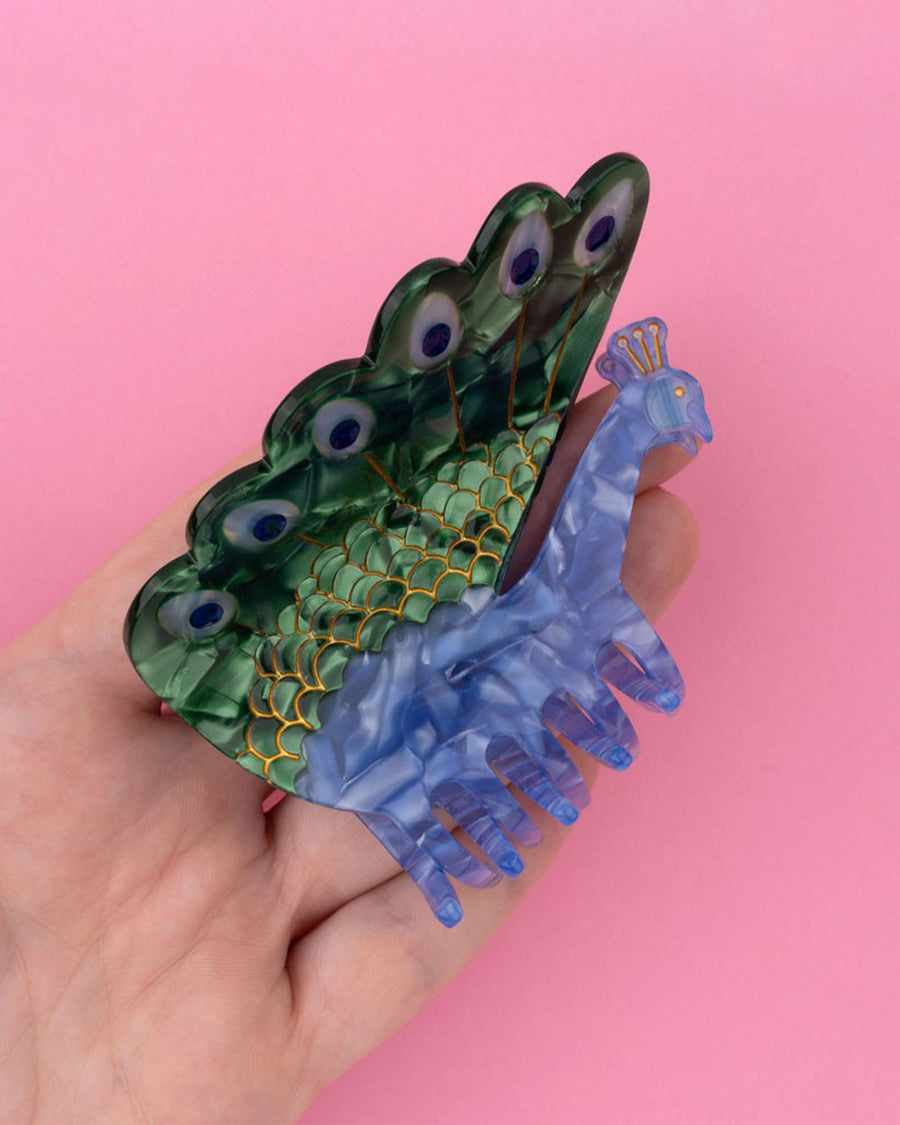 model holding purple peacock shaped hair claw