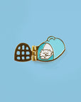 enamel pin with white cat sleeping inside of carrier with door open
