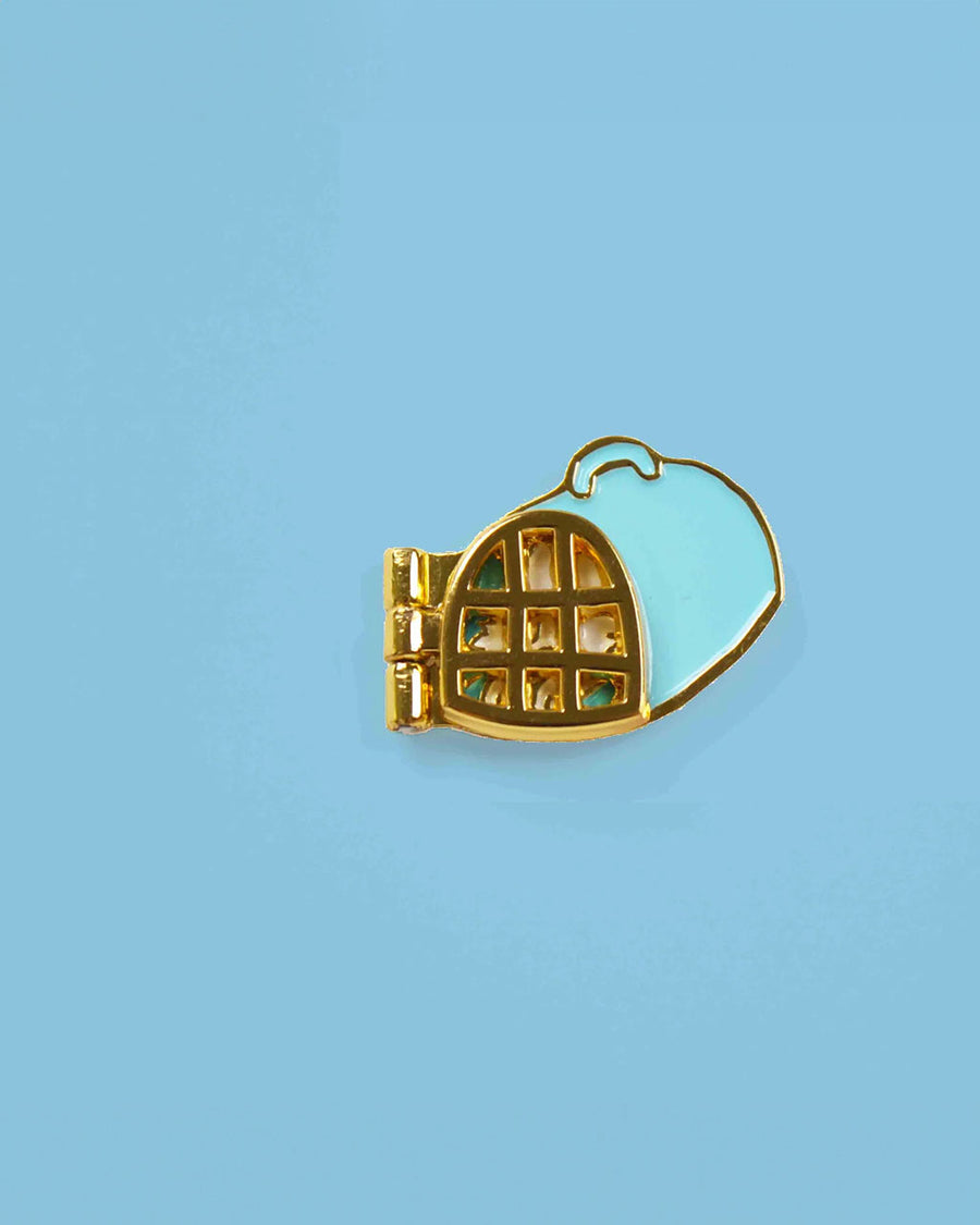 enamel pin with white cat sleeping inside of carrier with door closed
