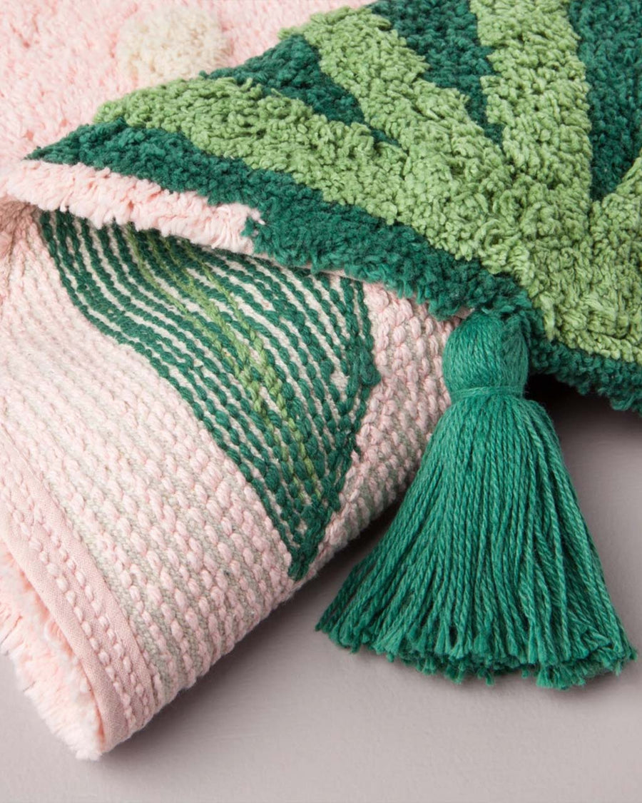 underside of pink strawberry bath rug with green stem tassel