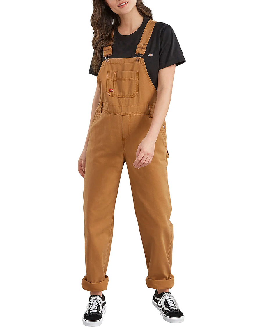 model wearing light brown cotton work overalls with front and slit pockets