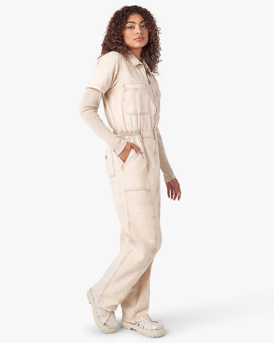 side view of model wearing acid wash stone coveralls with zipper front, short sleeves, patch front pockets and front seam down the legs