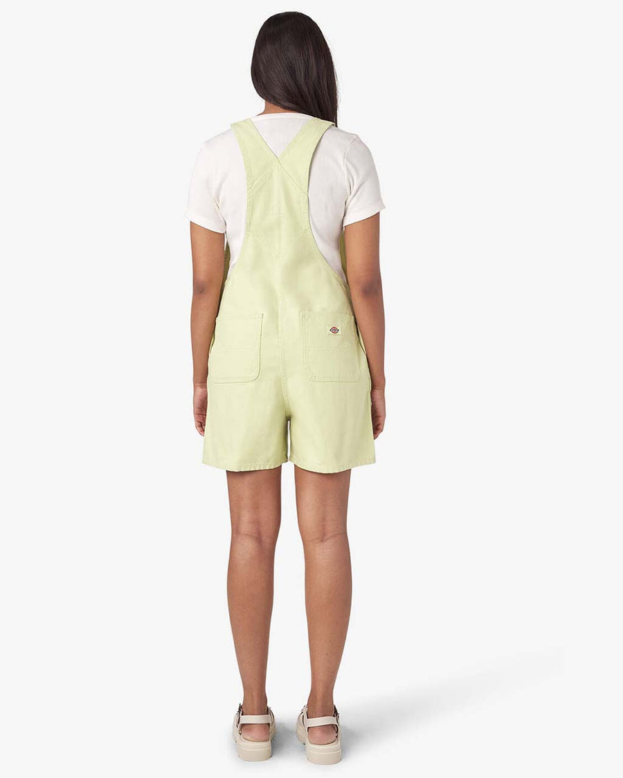 back view of model wearing pale green shortalls with dickies patch on the front bust pocket
