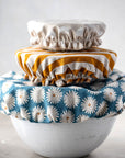 set of three fabric bowl covers: small white polka dots, medium gold and white stripe and large blue daisy on bowls