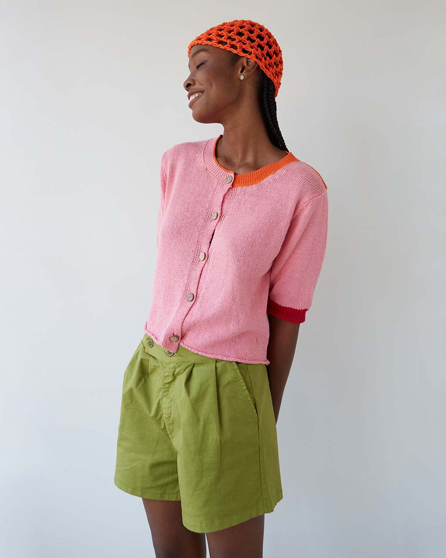 frontview of model wearing elbow length cardigan with bubblegum pink front and orange back