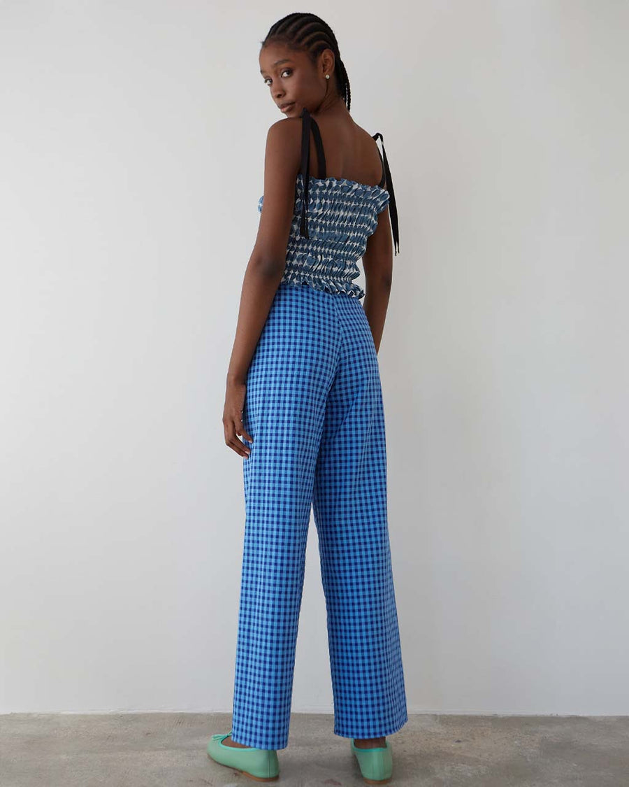 back view of model wearing blue gingham pants with patch pockets with dark blue trim and tie waist
