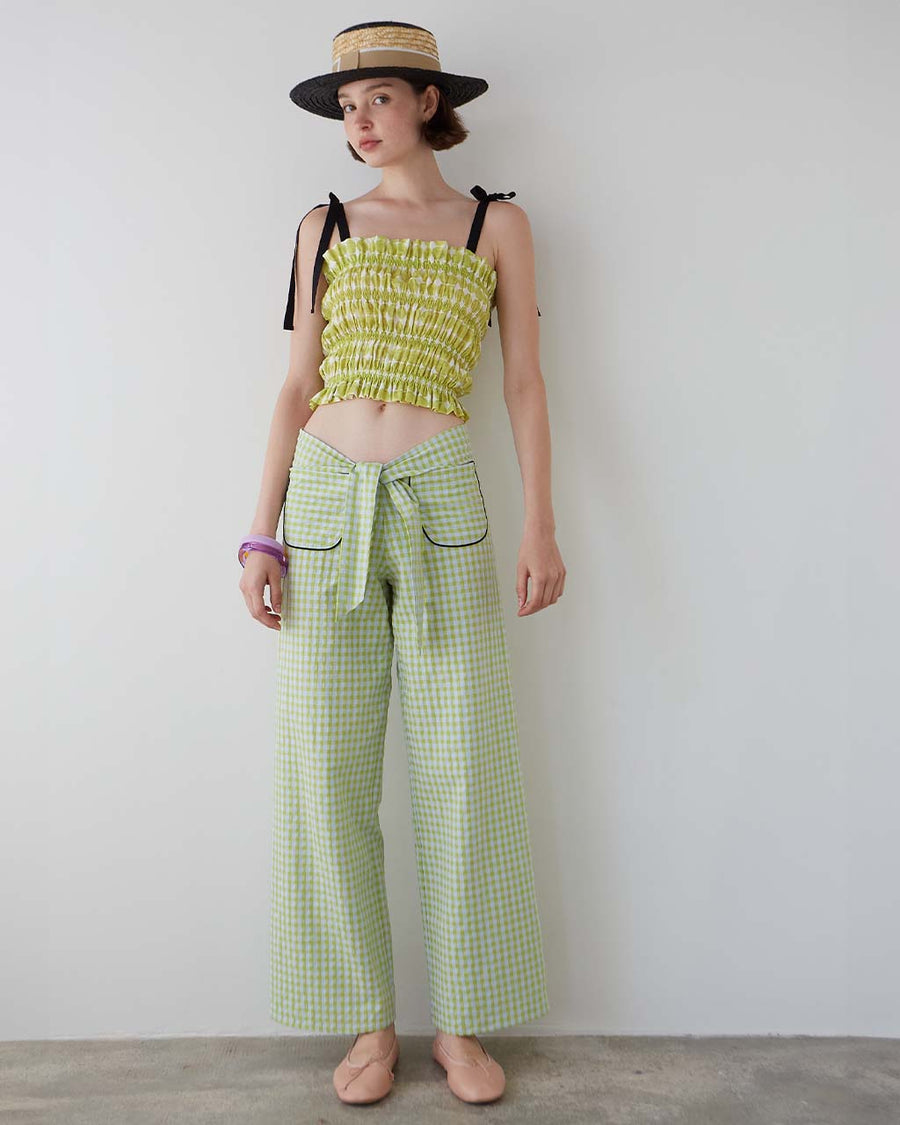 model wearing green gingham pants with patch pockets with black trim and tie waist