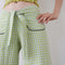 up close of model wearing green gingham pants with patch pockets with black trim and tie waist