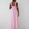back view of model wearing bubblegum pink cotton maxi dress with square neckline and patch pockets with bright yellow trim